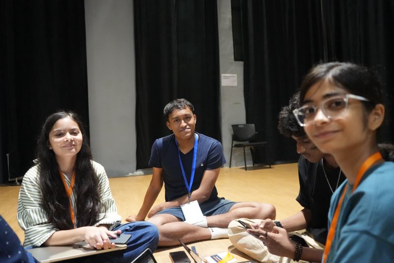 Three students sitting on the floor smile at the camera between rounds.